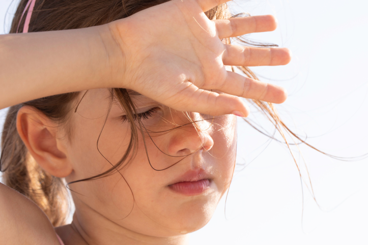 Child shielding their eyes in hot weather