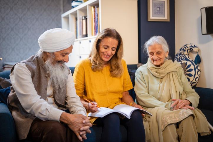 Three older adults smiling together while filling out a form.