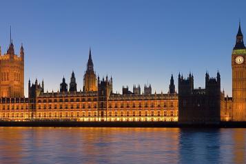 Palace of Westminster lit up brightly as the sun sets, from across the Thames.