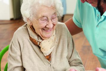 Older woman holding plate of food served by carer.