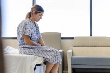 Female patient sitting on hospital bed.