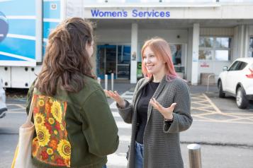 Two women talking outside of a women's services centre.