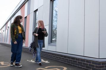 Two women walking and talking together.