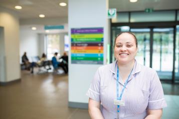 A healthcare professional smiling in the corridor of a hospital.
