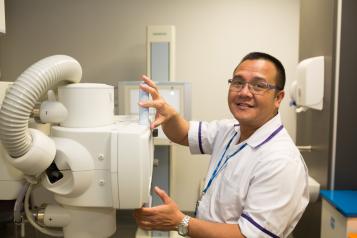 A medical professional using medical equipment and smiling.