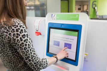 A person using a screen to check in for an appointment in a clinical setting.