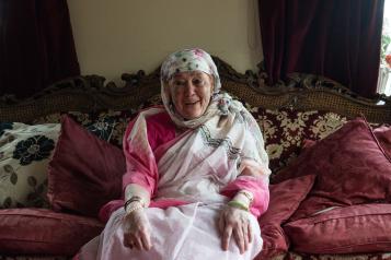 Older woman smiling on a sofa.