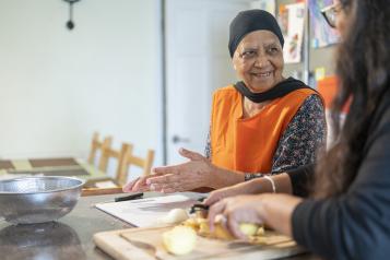 An older woman and another person preparing food together.