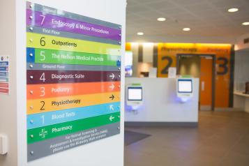 A photo of colourful signs directing service users to different departments in a hospital.