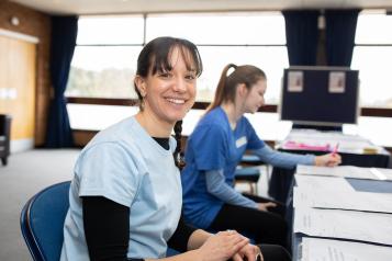 A healthcare professional smiling while sat at a desk.