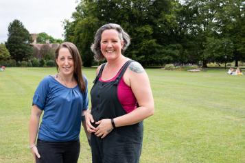 Two women standing outside in a park.