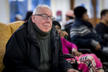 Older man sat down in a group environment. 