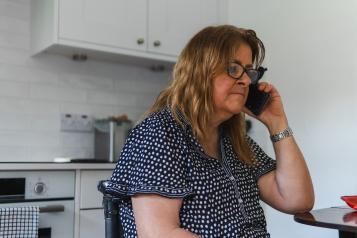 Woman using a phone in a kitchen.