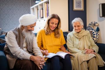 Three older adults smiling together indoors looking at a document