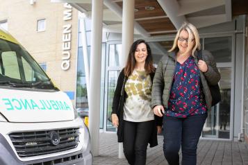 Two women walking past an ambulance.
