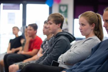 Children sat in chairs in a line.