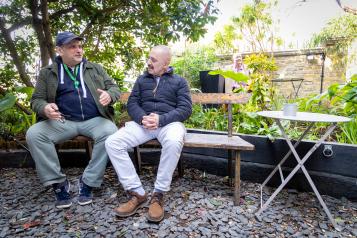 Two men chatting sat outside.