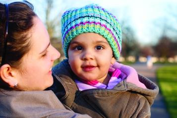 A baby being held by an adult in a park setting.