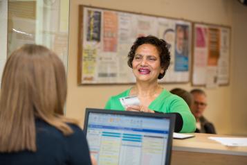 Woman talking at a GP reception counter.