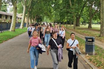 A group of people walking along a park avenue together.