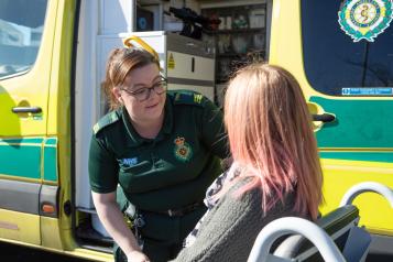 Ambulance worker supporting service user in front of an ambulance. 