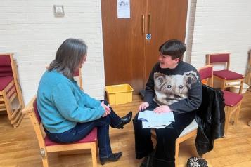 Two women talking while sat down.