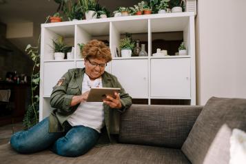 Woman using an iPad on a sofa indoors.