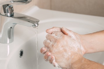 Hands being washed in a sink.