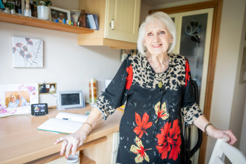 An older woman in a kitchen smiling.