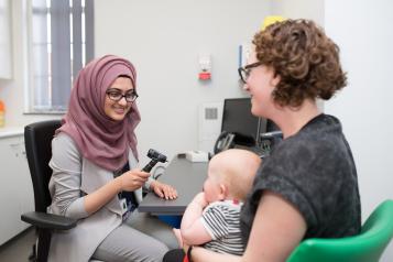 Female GP talking to female patient with baby