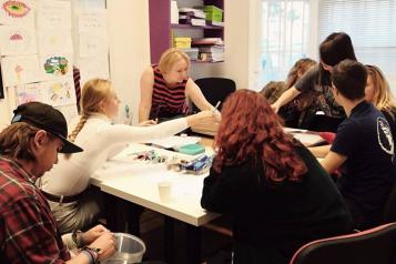 Young people round a table talking and working