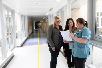 Nurse speaking to people in a hospital corridor