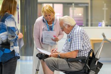 Man in a wheelchair with a lady standing next to him