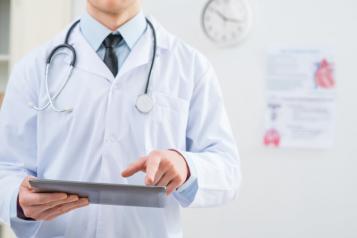 Doctor in white coat holding iPad, Left side of shot, Shoulder/Torso view