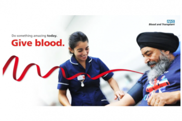 NHS Give Blood Poster, Nurse Smiling, Man Sitting Smiling Ready to Give Blood, Red Ribbon across Poster