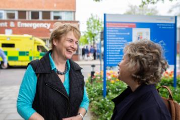 Two women speaking to one another outside a hospital