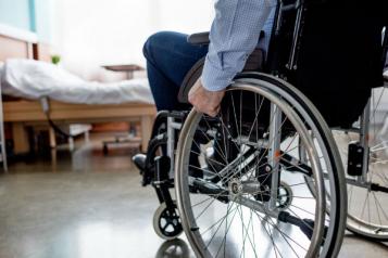 man in wheelchair by bed