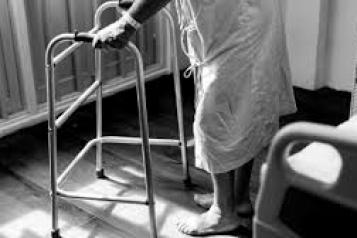 older person using walking frame in hospital