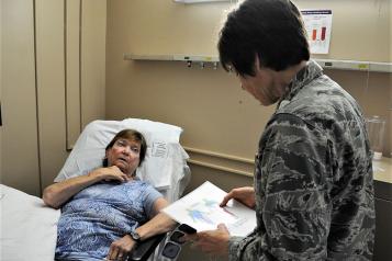 Female patient in hospital bed, doctor facing patient with clipboard