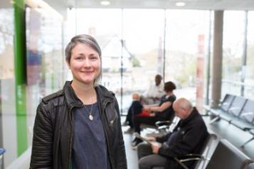 woman standing front of frame, to left, standing in GP Surgery