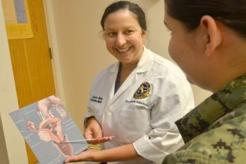 Doctor holding board, in front of patient