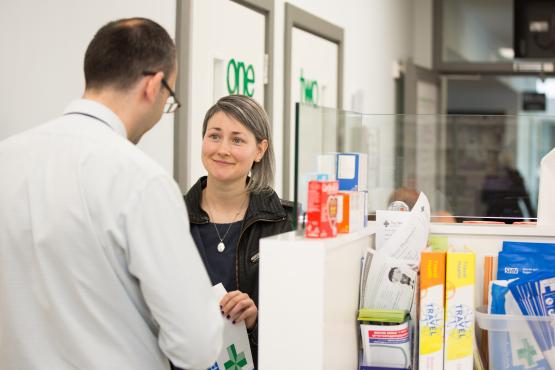 A woman serving a man over the counter in a pharmacy. 