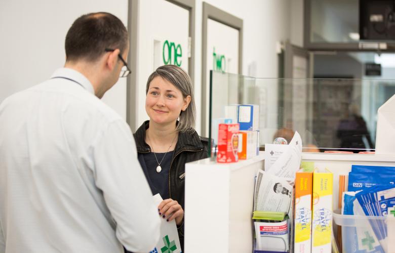 A woman serving a man over the counter in a pharmacy.