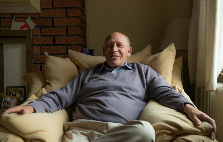 Portrait of an older man sat on the sofa.