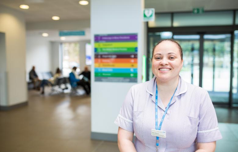 A healthcare professional smiling in the corridor of a hospital.