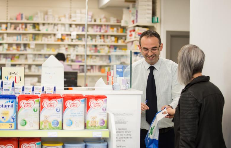 A pharmacist assisting a person in a pharmacy.