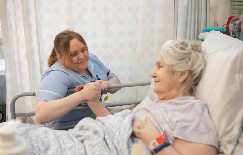 Medical professional holding the hand of a patient in a hospital setting.