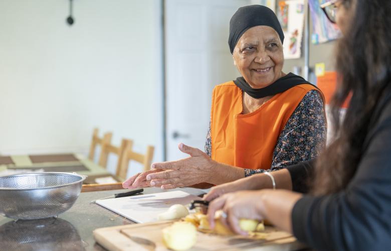 An older woman and another person preparing food together.