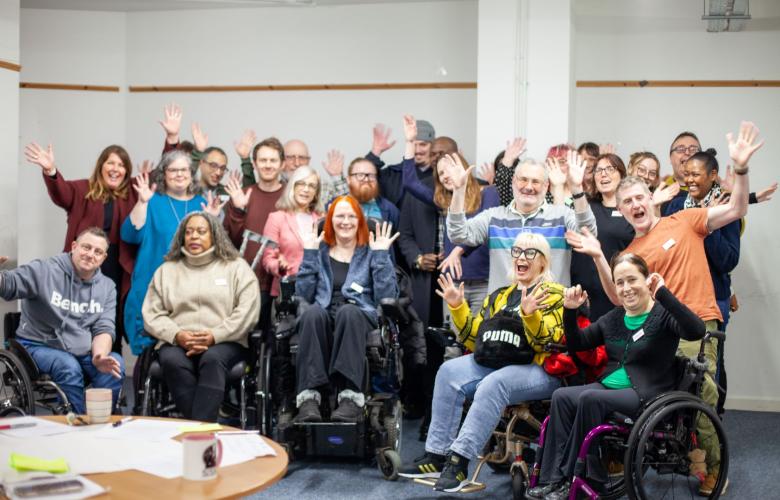 A group photo of a professional team in a conference room with everyone smiling and putting their arms up.