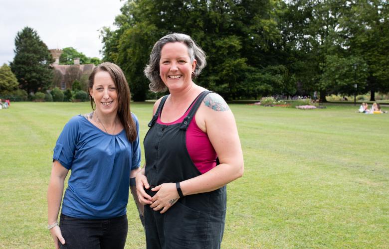 Two women standing outside in a park.